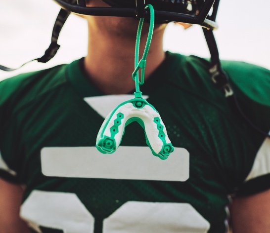 Teen with athletic mouthguard hanging from football helmet