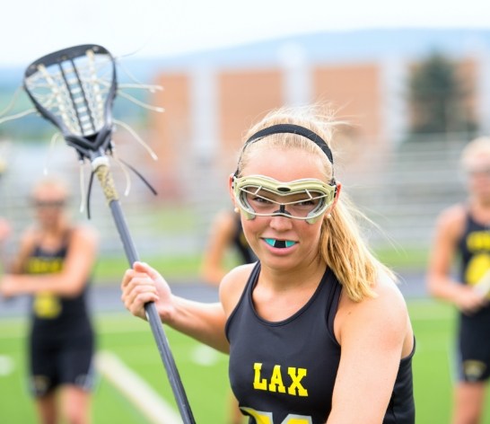 Teen girl playing field hockey with custom mouthguard