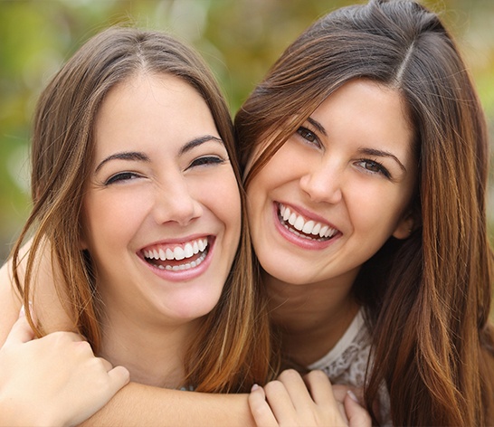 Two teens sharing bright smiles after teeth whitening