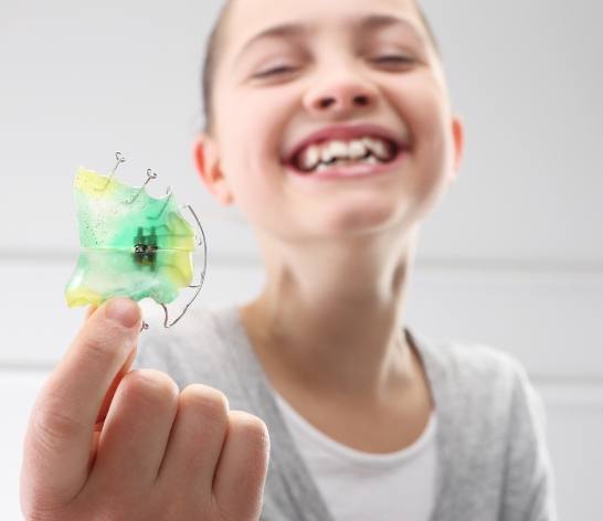 Child holding a retainer early interception orthodontic device