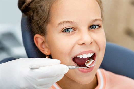 Girl in orange shirt undergoing dental exam