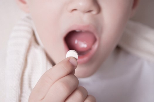 Closeup of child placing pill into mouth