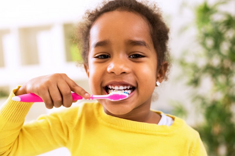 A young girl happily brushing her teeth